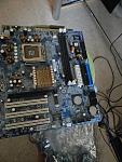 the (presumably) shorted motherboard (with the original motherboard just visible underneath at the top)
